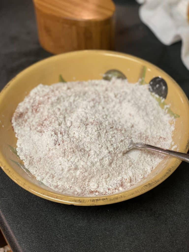 A yellow bowl filled with seasoned flour.